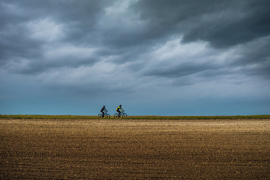 silhouette of a couple doing mountain biking under a stormy sky