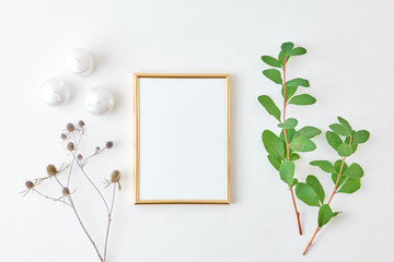 Flat lay composition with golden frame and branches with green leaves on a light background