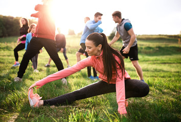 Fototapeta Large group of fit and active people doing exercise in nature, stretching. obraz