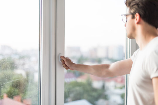 Young Man Opens The Window. Ventilating A House In Hot Weather.