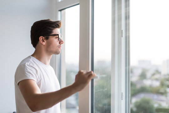 Young man opens the window. Ventilating a house in hot weather.