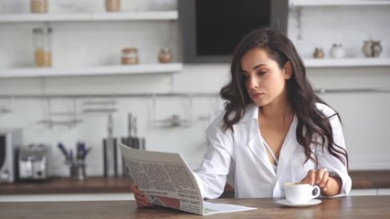 woman reading newspaper and drinking coffee - Powered by Adobe