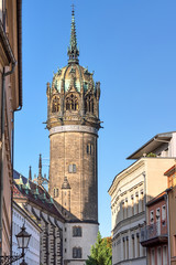 Fototapeta na wymiar Häuserzeile und Turm der Schlosskirche in der Schlossstraße in der Lutherstadt Wittenberg, Sachsen-Anhalt
