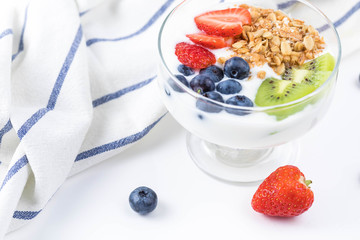 Plate of homemade granola with yogurt and fresh berries: strawberry, kiwi and blueberry on white  background  from top view