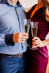New Year 2020. New Year mood. Table with a gold tablecloth, decorated with candles and tableware for celebration. Festive still life by candlelight.A man pours champagne into a glass. Close-up.