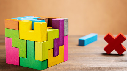 Missed items are seting in the colorful wooden cube puzzle on the brown table. Geometric shapes on...