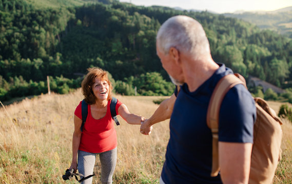 Senior tourist couple travellers hiking in nature, walking and talking.