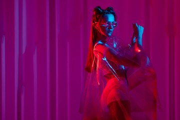 Cyberpunk and neon, a young trend girl in a transparent latex raincoat.