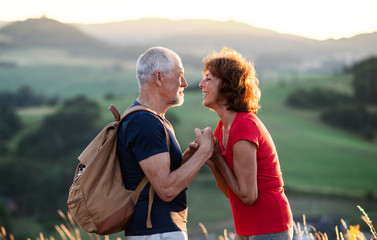Naklejka premium Senior tourist couple hikers with backpack standing in nature, resting.