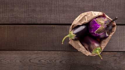 Fresh eggplant inside paper package on wooden background