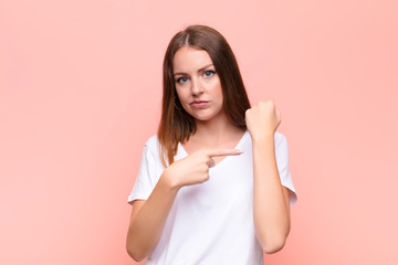 young red head woman looking impatient and angry, pointing at watch, asking for punctuality, wants...