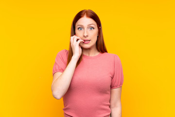 Young redhead woman over isolated yellow background nervous and scared