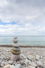 Piedras de distintos tamaños apiladas en forma piramidal junto al mar.