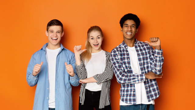 Diverse classmates pointing fingers at themselves, posing to camera