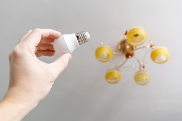 Hand screwing new lightbulb into ceiling lamp