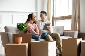 Smiling couple talking using tablet computer on moving relocation day