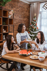 mother wearing apron serving food for lunch to her family at home