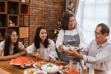 mother wearing apron serving food for lunch to her family at home
