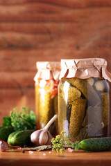 Canned gherkins in jar, fresh dill, garlic, pepper over wooden background. Copy space. Harvest preserve concept. Homemade pickled and canned vegetables concept. Seasonal harvest. Probiotic food