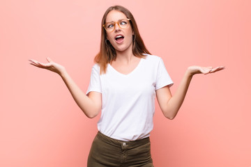young red head woman shrugging with a dumb, crazy, confused, puzzled expression, feeling annoyed...