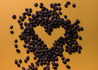 coffee beans on orange background with heart silhouette