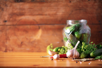 Pickling cucumbers in cans. Ingredients for marinated gherkins, glass jar, garlic, dill, salt, pepper on green background. Copy space. Concept of vegetables preservation.
