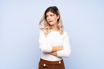 Young teenager girl over isolated blue background with confuse face expression