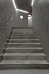 Fototapeta na wymiar Empty modern reinforced concrete staircase with steel handrail and round window. Industrial style
