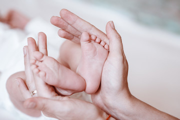 Obraz na płótnie Canvas Newborn Baby's feet on female hands closeup.