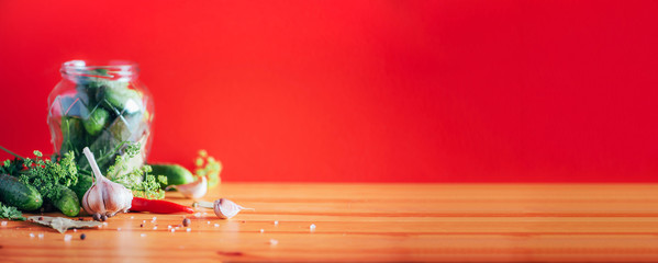 Ingredients, spices and herbs for canning cucumbers on red background. Copy space. Dill flowers, bay leaf, horseradish leaf, garlic, gherkins.