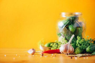 Ingredients, spices and herbs for canning cucumbers on yellow background. Copy space. Dill flowers, bay leaf, horseradish leaf, garlic, gherkins.