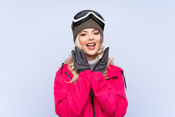 Skier teenager girl with snowboarding glasses over isolated blue background with surprise facial expression