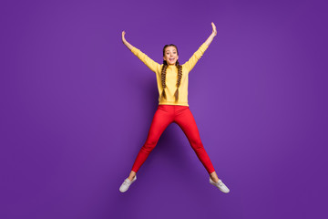 Fototapeta na wymiar Full body photo of crazy youngster lady jumping high spending best free time spread hands star shape wear casual yellow pullover red trousers isolated purple color background