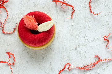 Contemporary raspberry mini mousse tart covered with red velvet spray decorated with chocolate feathers on light background