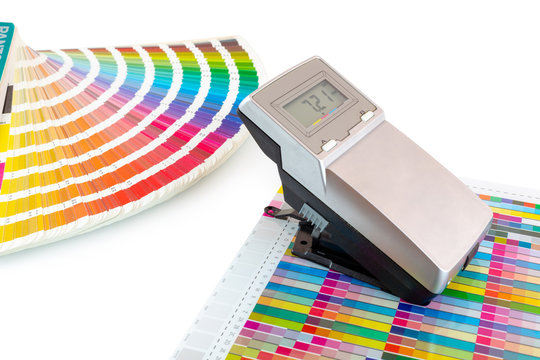 Printed color swatch, density meter and paint guide isolated on white background - clipping path. Measuring density of magenta color in printing process. Densitometer and ink sampler. Color checking.