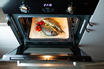 Cooking fish in the oven. Cooking dorado with cherry tomatoes and herbs on parchment in the oven....