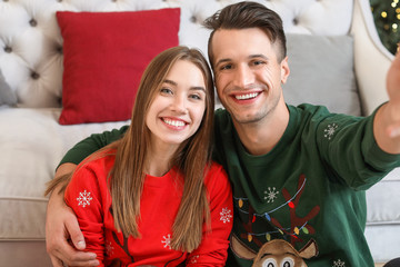 Happy young couple taking selfie on Christmas eve at home © Pixel-Shot