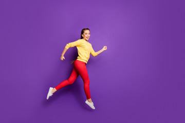 Fototapeta na wymiar Full body profile photo of millennial lady jumping high rushing sale shopping speed running race wear casual yellow pullover red trousers isolated purple color background
