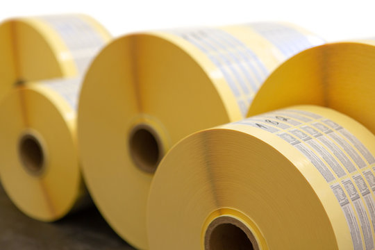 Reels of printed adhesive labels before slitting or cutting isolated on white background. Bunch of printed rolls.