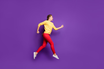 Fototapeta na wymiar Full length profile photo of funny millennial lady jumping high rushing sale shopping speed running wear casual yellow pullover red trousers isolated purple color background