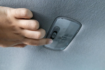 Close up hands turning switch on or off car ceiling reading light.
