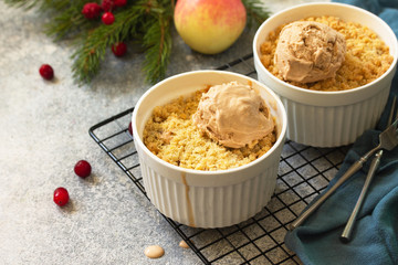 Homemade winter dessert. An apple crumbles with cranberries served with a ball of caramel ice cream on a stone or slate countertop background.