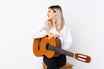 Teenager girl with guitar over isolated white background looking side