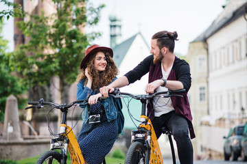 Young tourist couple travellers with electric scooters in small town.