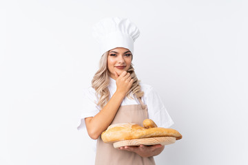 Teenager girl in chef uniform. Female baker holding a table with several breads over isolated white background laughing