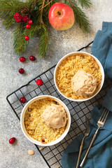 Homemade winter dessert. An apple crumbles with cranberries served with a ball of caramel ice cream on a stone or slate countertop background. Top view of a flat lay.