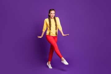 Fototapeta na wymiar Full length photo of funny millennial lady walking down street long braids amazing warm sunny day wear casual yellow pullover red trousers isolated purple color background