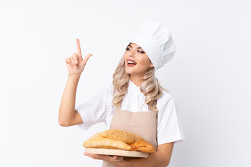 Teenager girl in chef uniform. Female baker holding a table with several breads over isolated white background pointing with the index finger a great idea