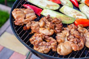 Assortment of fresh healthy colored vegetables, chicken meat grilled on BBQ grilling over a hot fire coals against green grass on barbecue. Concept summer party, outdoor meal, open air cook