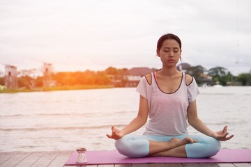 Fototapeta na wymiar Young healthy woman practice yoga in the morning with the lake as background. Concept of healthy.